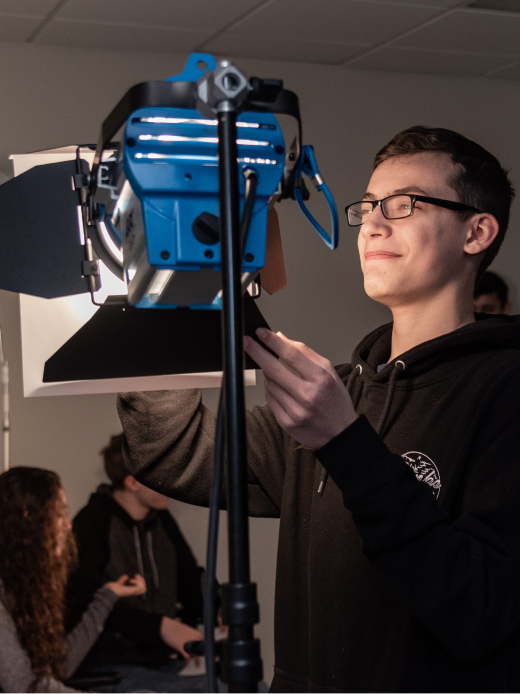 Male student adjusting a light on a film set