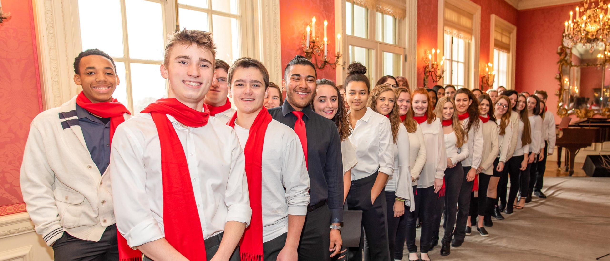 Group of students wearing red scarves at a function where they will be singing carols
