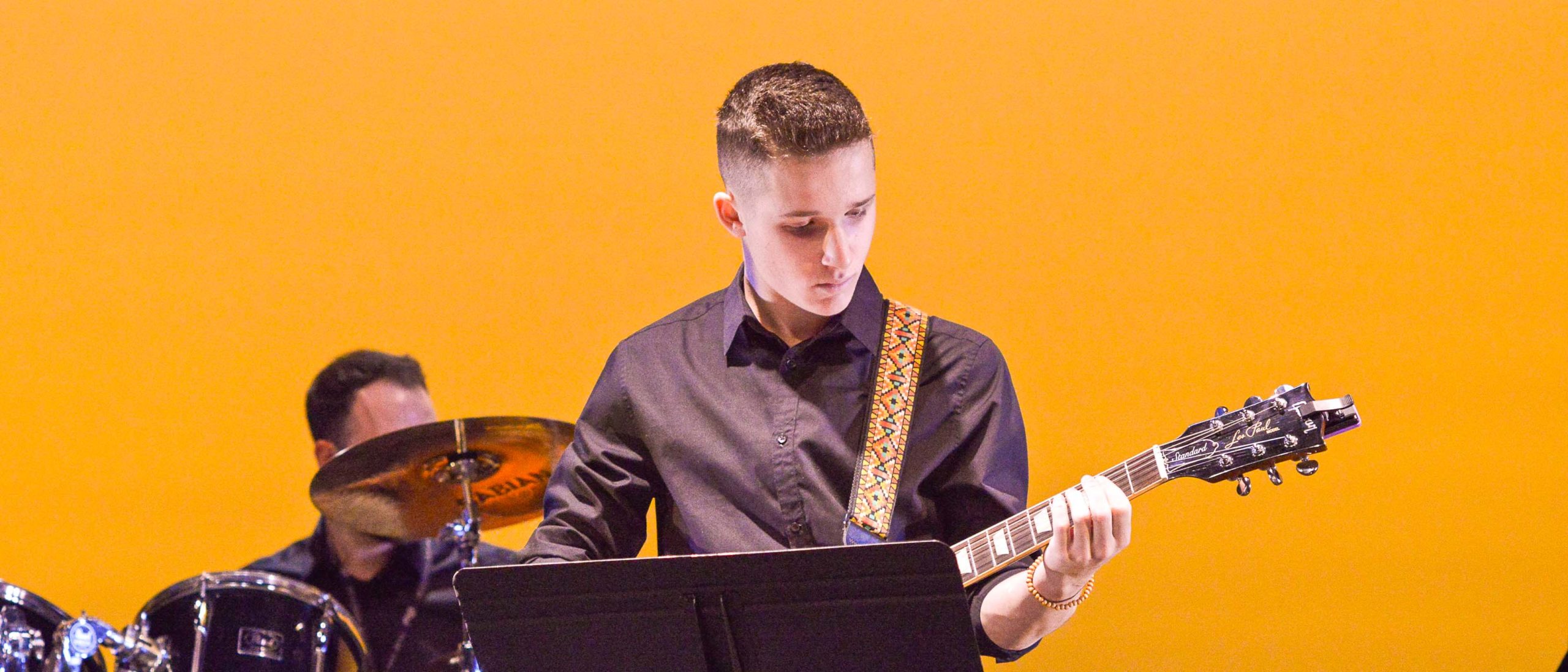 Boy student playing the guitar on stage