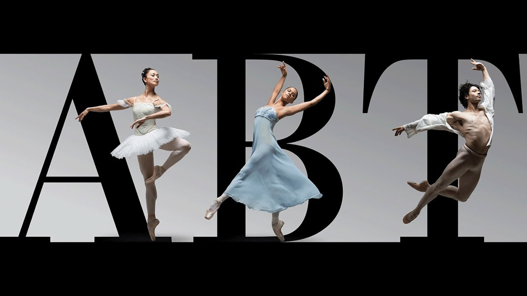 Ballet dancers dancing in front of the American Ballet Theatre logo